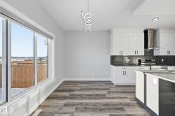 Kitchen with white cabinets, wall chimney range hood, light wood-type flooring, and electric stove - 