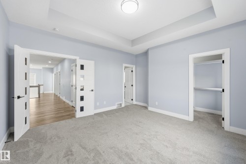 Unfurnished bedroom featuring light carpet, a walk in closet, and a raised ceiling - 829 Morris Avenue, Leduc, AB - Indoor Photo Showing Other Room