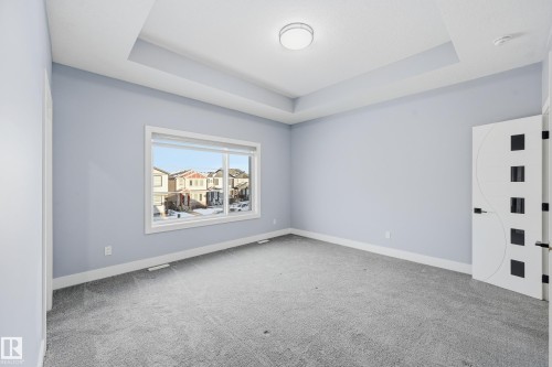 Empty room featuring a raised ceiling and light carpet - 829 Morris Avenue, Leduc, AB - Indoor Photo Showing Other Room