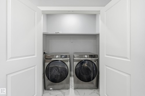 Washroom with marble look tiles and separate washer and dryer - 829 Morris Avenue, Leduc, AB - Indoor Photo Showing Laundry Room
