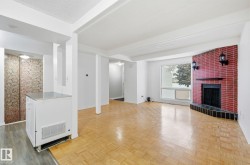 Unfurnished living room featuring a brick fireplace and parquet flooring - 