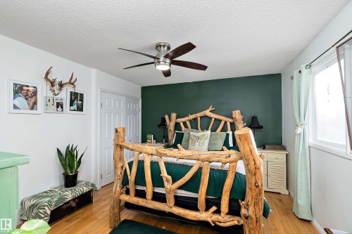 Bedroom featuring a textured ceiling, hardwood / wood-style flooring, and ceiling fan - 145 Plum Crescent, Wetaskiwin, AB - Indoor Photo Showing Bedroom