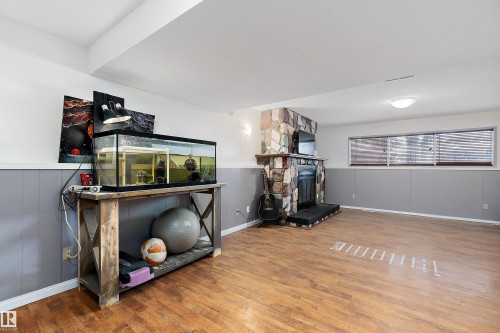 Workout area featuring a fireplace, wood finished floors, and wainscoting - 145 Plum Crescent, Wetaskiwin, AB - Indoor