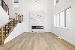 Unfurnished living room with wood finished floors, a premium fireplace, a high ceiling, and stairs - 