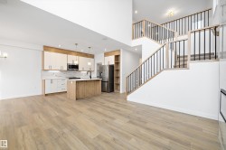 Kitchen with open floor plan, stainless steel appliances, decorative light fixtures, a kitchen island with sink, and light wood-style floors - 