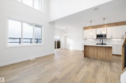 Kitchen with a chandelier, white cabinetry, open floor plan, decorative light fixtures, and a towering ceiling - 
