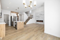 Kitchen with decorative light fixtures, an island with sink, appliances with stainless steel finishes, open floor plan, and a fireplace - 