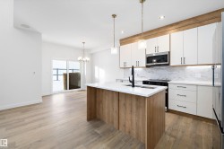 Kitchen featuring white cabinetry, hanging light fixtures, a center island with sink, decorative backsplash, and recessed lighting - 