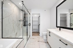 Full bathroom with a walk in closet, a marble finish shower, vanity, light marble finish floors, and a tub with marble appearance - 