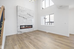 Unfurnished living room featuring light wood-style floors, a high ceiling, and a high end fireplace - 