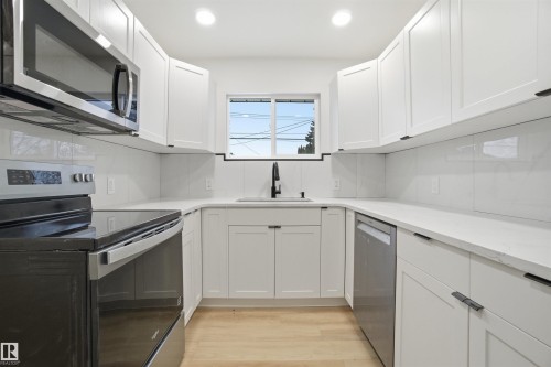 Kitchen featuring appliances with stainless steel finishes, white cabinets, light wood-style floors, light stone countertops, and recessed lighting - 5711 95 Avenue, Edmonton, AB - Indoor Photo Showing Kitchen