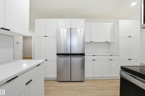 Kitchen featuring freestanding refrigerator, light wood-type flooring, white cabinetry, light stone counters, and black range with electric stovetop - 5711 95 Avenue, Edmonton, AB - Indoor Photo Showing Kitchen
