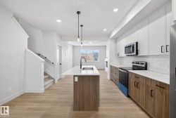Kitchen featuring brown cabinetry, range with electric cooktop, a kitchen island with sink, modern cabinets, and light wood-style floors - 