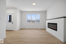 Unfurnished living room featuring light wood finished floors, a glass covered fireplace, and a textured ceiling - 