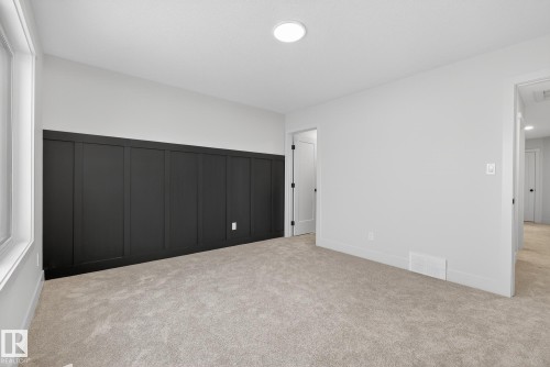 Unfurnished bedroom featuring light colored carpet, wainscoting, and a decorative wall - 119 Brickyard Drive, Stony Plain, AB - Indoor Photo Showing Other Room