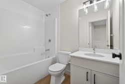 Full bathroom with vanity, washtub / shower combination, and light wood-style flooring - 