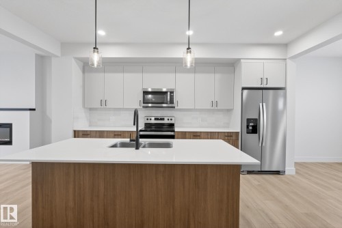 Kitchen with decorative backsplash, white cabinets, stainless steel appliances, pendant lighting, and a center island with sink - 119 Brickyard Drive, Stony Plain, AB - Indoor Photo Showing Kitchen With Double Sink With Upgraded Kitchen