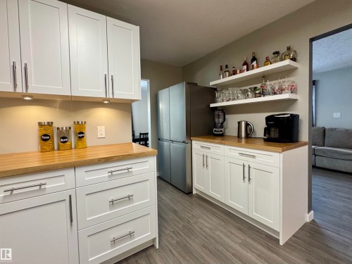 Kitchen featuring wooden counters, open shelves, white cabinetry, freestanding refrigerator, and dark wood finished floors - 5140 52 Avenue, Ryley, AB - Indoor Photo Showing Kitchen