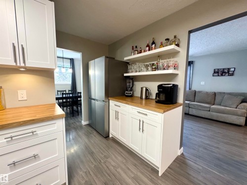 Kitchen with open shelves, butcher block counters, white cabinets, freestanding refrigerator, and open floor plan - 5140 52 Avenue, Ryley, AB - Indoor Photo Showing Kitchen