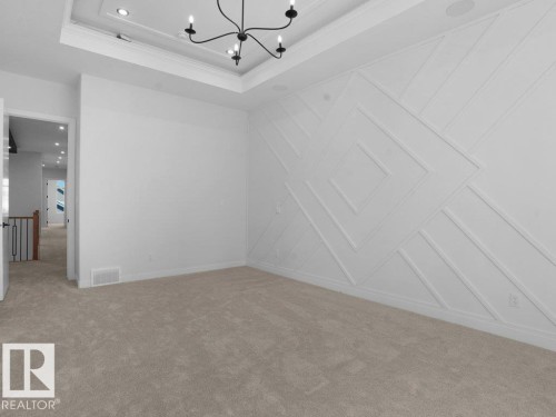 Empty room featuring a chandelier, crown molding, light colored carpet, and a tray ceiling - 6131 Crawford Drive, Edmonton, AB - Indoor Photo Showing Other Room