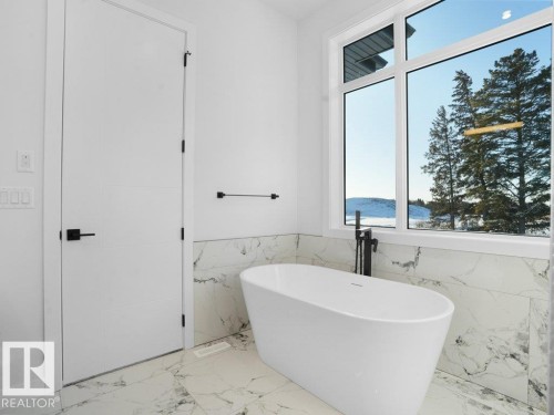 Bathroom with marble tiled flooring, wainscoting, tile walls, and a freestanding bath - 6131 Crawford Drive, Edmonton, AB - Indoor Photo Showing Bathroom
