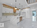 Kitchen with white cabinetry, light marble finish flooring, light stone countertops, an island with sink, and recessed lighting - 6131 Crawford Drive, Edmonton, AB  - Indoor Photo Showing Kitchen With Upgraded Kitchen 