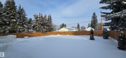 Yard layered in snow with a fenced backyard - 