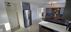 Kitchen featuring stainless steel appliances, pendant lighting, light countertops, and a desk - 