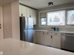 Kitchen featuring appliances with stainless steel finishes, white cabinets, light stone countertops, and tasteful backsplash - 