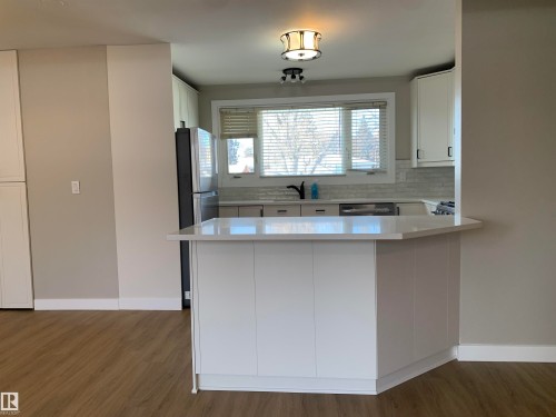 Kitchen with white cabinets, a peninsula, dark wood finished floors, and backsplash - 10816 163 Street, Edmonton, AB - Indoor Photo Showing Kitchen