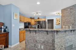 Kitchen with a breakfast bar, stainless steel appliances, light stone counters, and a peninsula - 