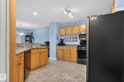 Kitchen featuring appliances with stainless steel finishes, light stone countertops, decorative light fixtures, and brown cabinetry - 