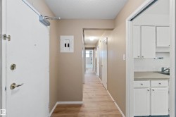 Hallway featuring a textured ceiling, light wood-type flooring, and electric panel - 