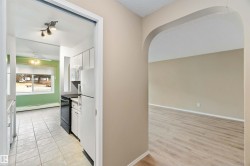 Kitchen with white cabinetry, white appliances, a baseboard heating unit, a ceiling fan, and light tile patterned floors - 