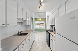 Kitchen featuring white appliances, light countertops, white cabinets, light tile patterned floors, and track lighting - 