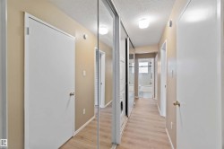 Hall with a textured ceiling, light wood finished floors, and stacked washing machine and dryer - 