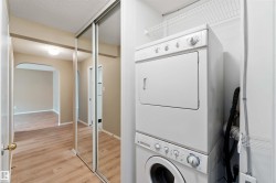 Washroom with estacked washer and dryer, light wood finished floors, arched walkways, and a textured ceiling - 
