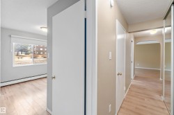 Corridor featuring a baseboard radiator, light wood-style floors, arched walkways, and a textured ceiling - 