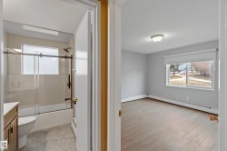 Bathroom featuring shower / bath combination with glass door, vanity, a baseboard radiator, and a textured ceiling - 