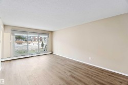 Empty room with a baseboard heating unit, a textured ceiling, and wood finished floors - 