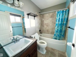 Full bathroom featuring shower / bathtub combination with curtain, vanity, plenty of natural light, light tile patterned floors, and a textured ceiling - 