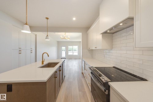 Kitchen featuring electric range, white cabinets, light wood finished floors, a kitchen island with sink, and recessed lighting - 199 Stonehouse Way, Leduc, AB - Indoor Photo Showing Kitchen With Upgraded Kitchen