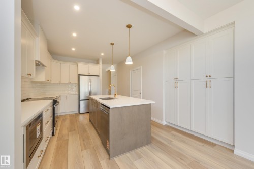 Kitchen featuring white cabinetry, decorative light fixtures, recessed lighting, light wood-type flooring, and a center island with sink - 199 Stonehouse Way, Leduc, AB - Indoor Photo Showing Kitchen