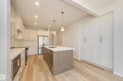 Kitchen featuring white cabinetry, decorative light fixtures, recessed lighting, light wood-type flooring, and a center island with sink - 
