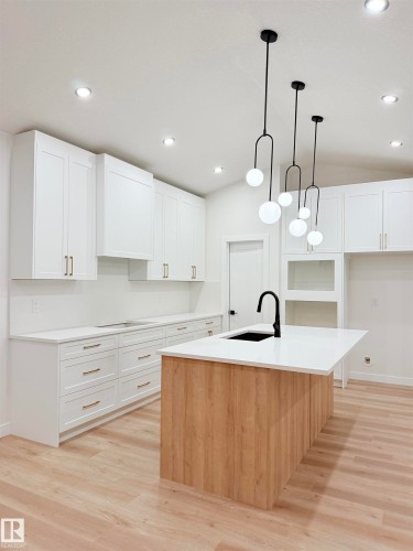 Kitchen featuring white cabinets, decorative light fixtures, a center island with sink, light wood-style floors, and recessed lighting - 3320 Chickadee Drive, Edmonton, AB - Indoor Photo Showing Kitchen With Upgraded Kitchen