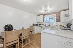 Kitchen with white cabinetry, light stone counters, light wood-style flooring, and white appliances - 