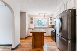 Kitchen with stainless steel appliances, arched walkways, a center island, hanging light fixtures, and glass insert cabinets - 
