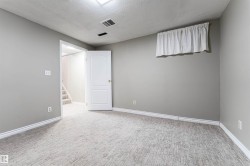 Unfurnished room featuring a textured ceiling, stairway, and light carpet - 