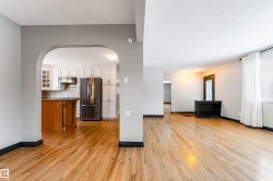 Kitchen featuring glass insert cabinets, freestanding refrigerator, a textured ceiling, arched walkways, and light wood-style flooring - 