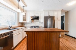 Kitchen featuring butcher block countertops, appliances with stainless steel finishes, pendant lighting, backsplash, and light wood-type flooring - 